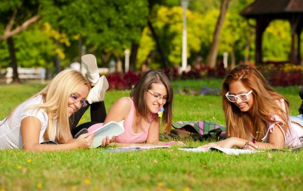 3 dziewczyny uczą sie języka angielskiego leżąc w parku na trwaie