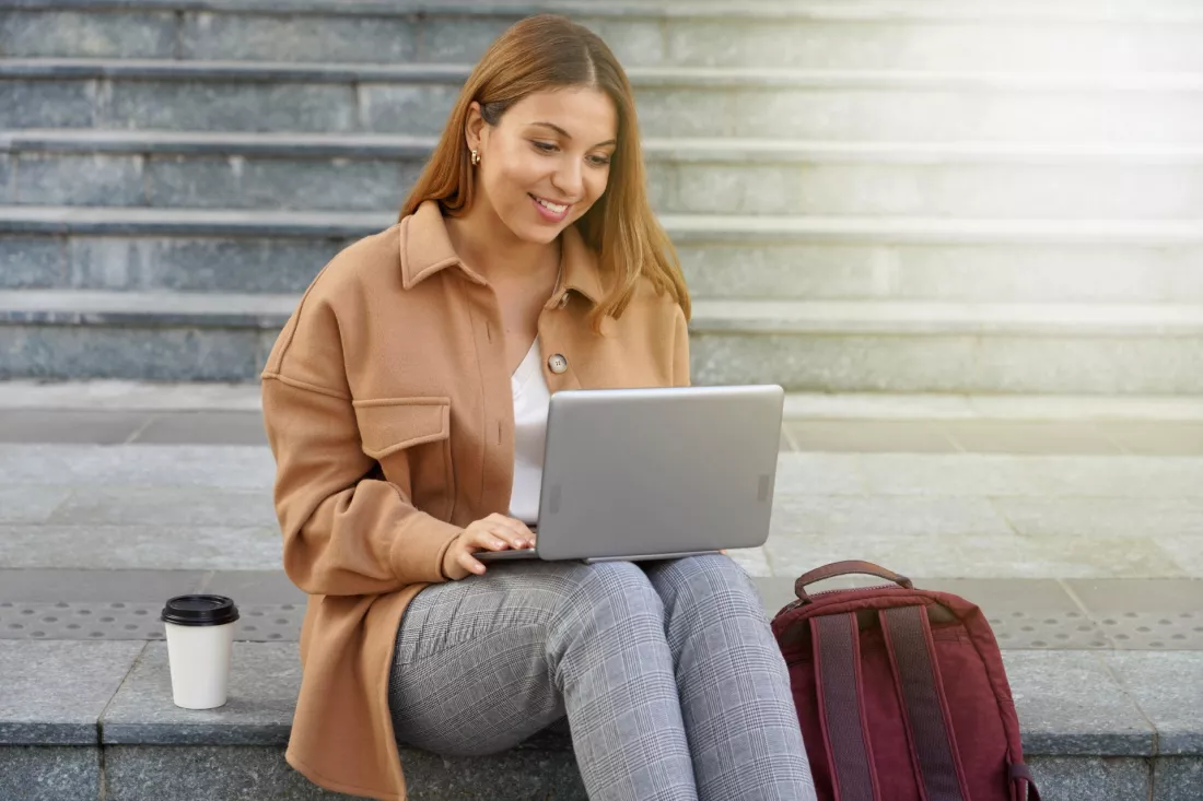 Studentka z laptopem uczy sie jezyka online przed wyjazdem na Erasmusa