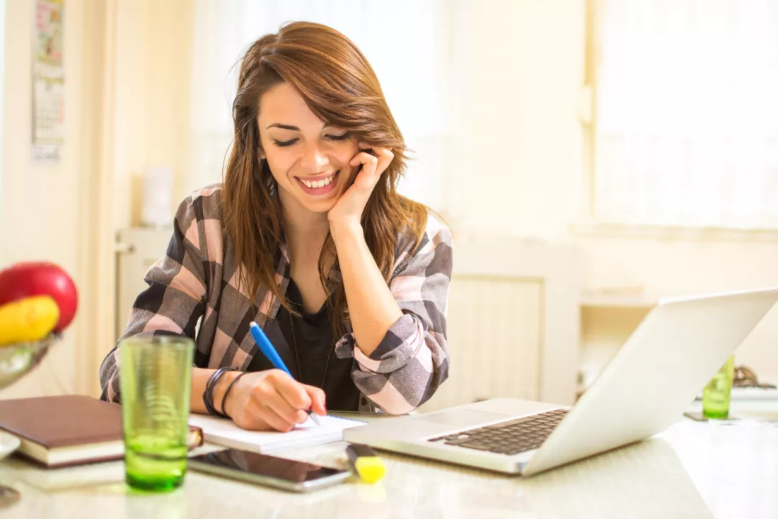 Studentka uczy się przy biurku z książkami i laptopem